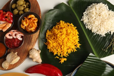 Photo of Cut banana leaf with different food on white table, flat lay. Healthy eco serving