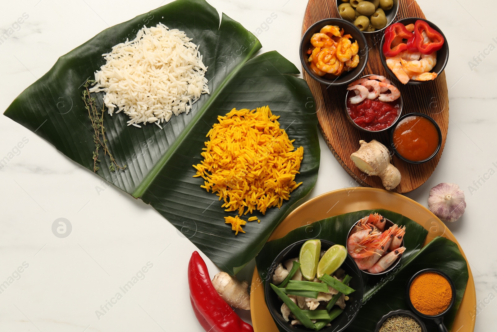 Photo of Cut banana leaves with different food, spices and sauce on white table, flat lay