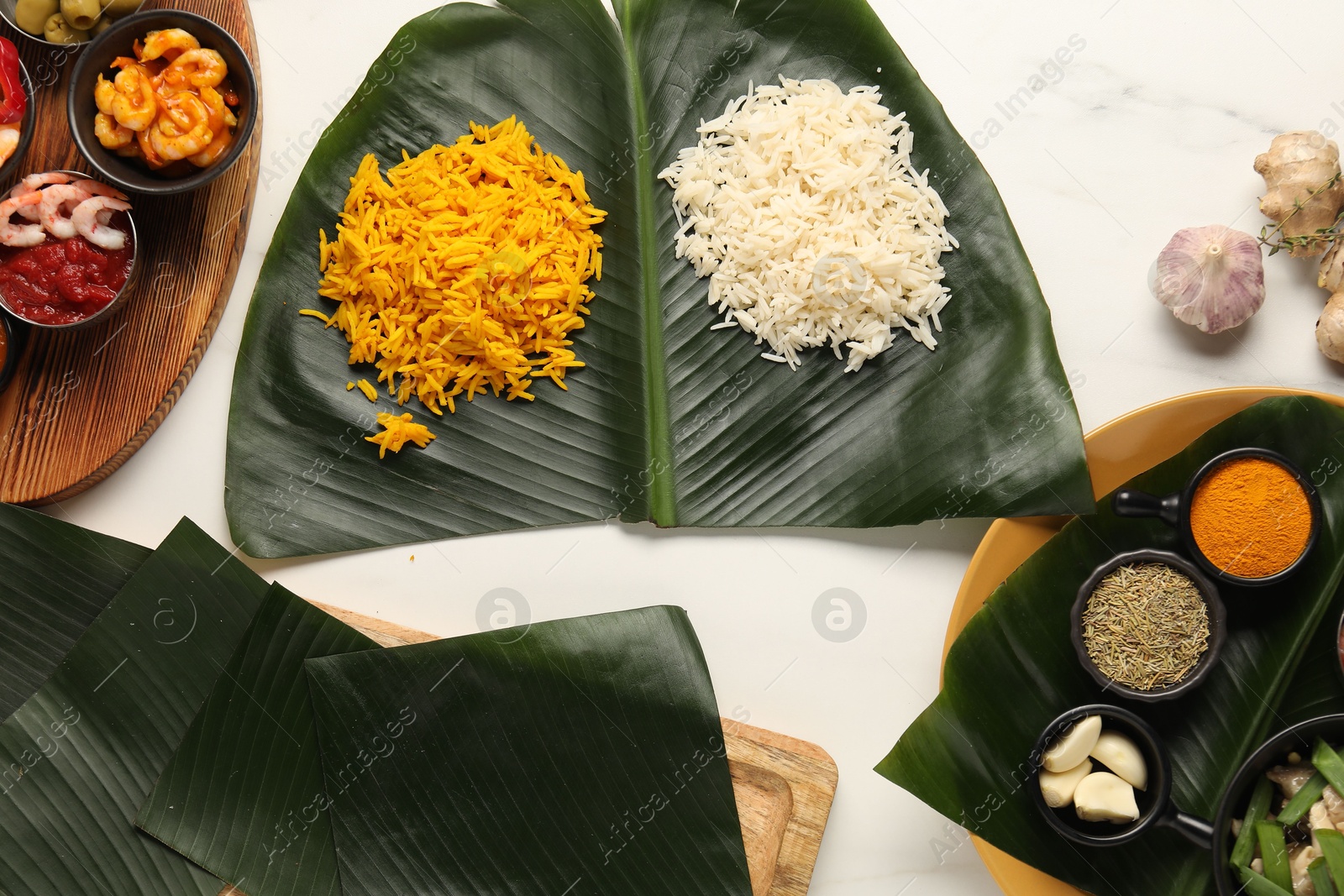 Photo of Cut banana leaves with different food, spices and sauce on white table, flat lay