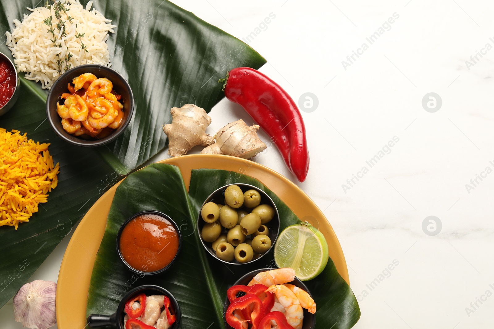 Photo of Cut banana leaves with different food and sauce on white marble table, flat lay. Space for text