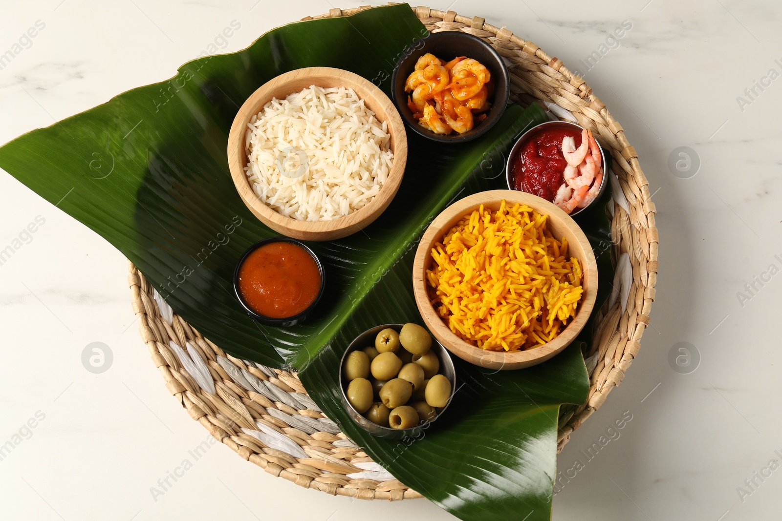 Photo of Piece of banana leaf with different food and sauce on white table, top view. Healthy eco serving