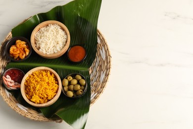 Photo of Piece of banana leaf with different food and sauce on white table, top view. Space for text