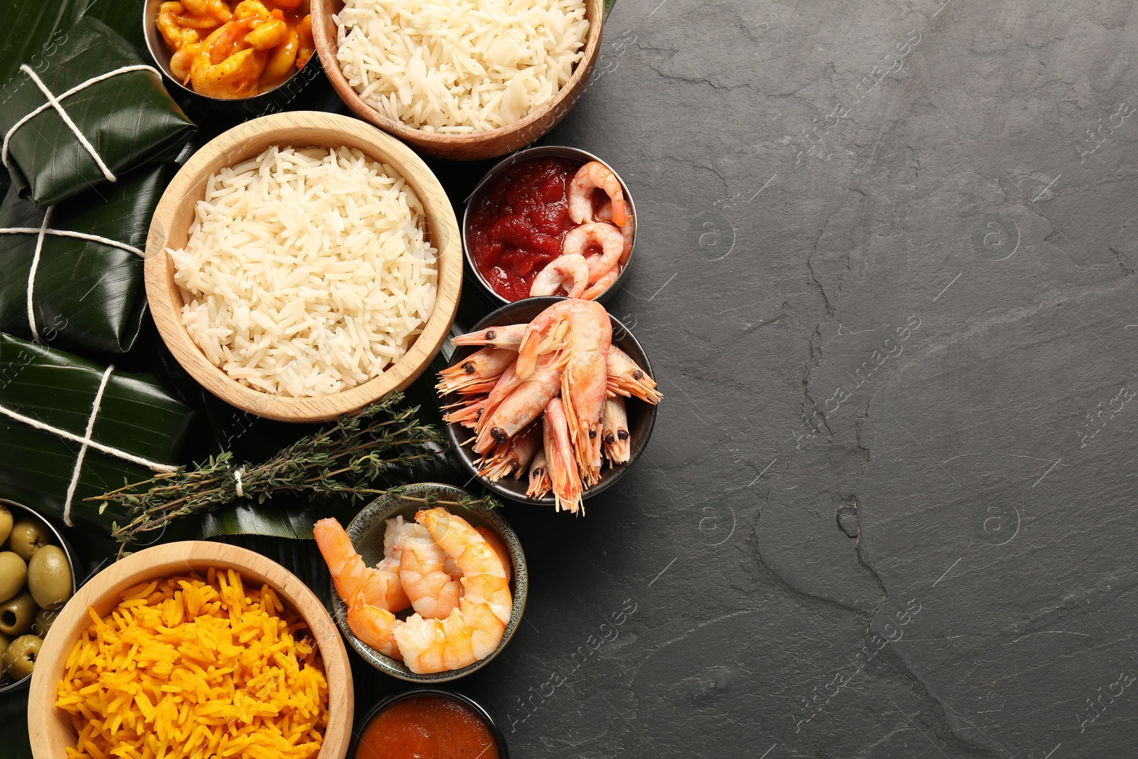 Photo of Cut banana leaves with different food and sauce on dark textured table, flat lay. Space for text