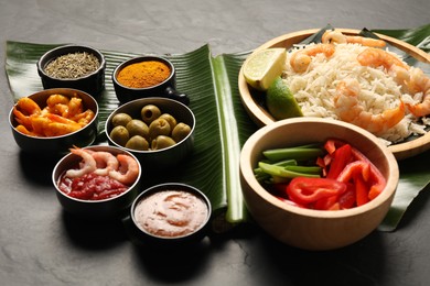 Photo of Piece of banana leaf with different food, spices and sauce on grey table, closeup. Healthy eco serving