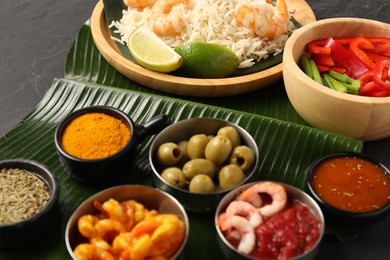 Photo of Piece of banana leaf with different food, spices and sauce on grey table, closeup. Healthy eco serving