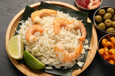 Photo of Pieces of banana leaf with rice, shrimps and lime on grey textured table, closeup