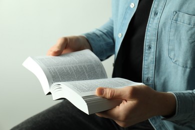 Photo of Man reading Holy Bible in English language on light background, closeup