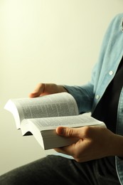 Photo of Man reading Holy Bible in English language on light background, closeup