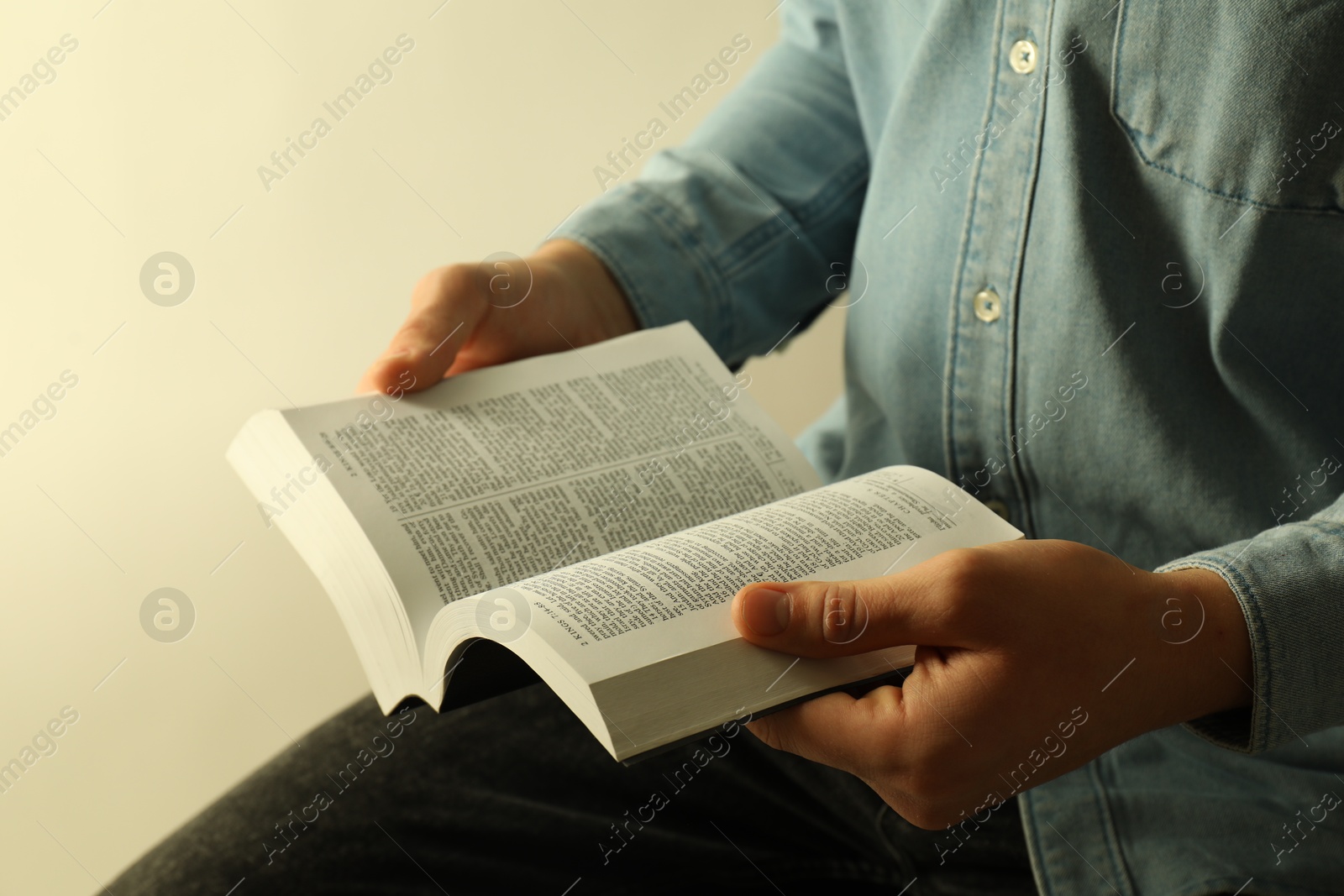 Photo of Man reading Holy Bible in English language on light background, closeup