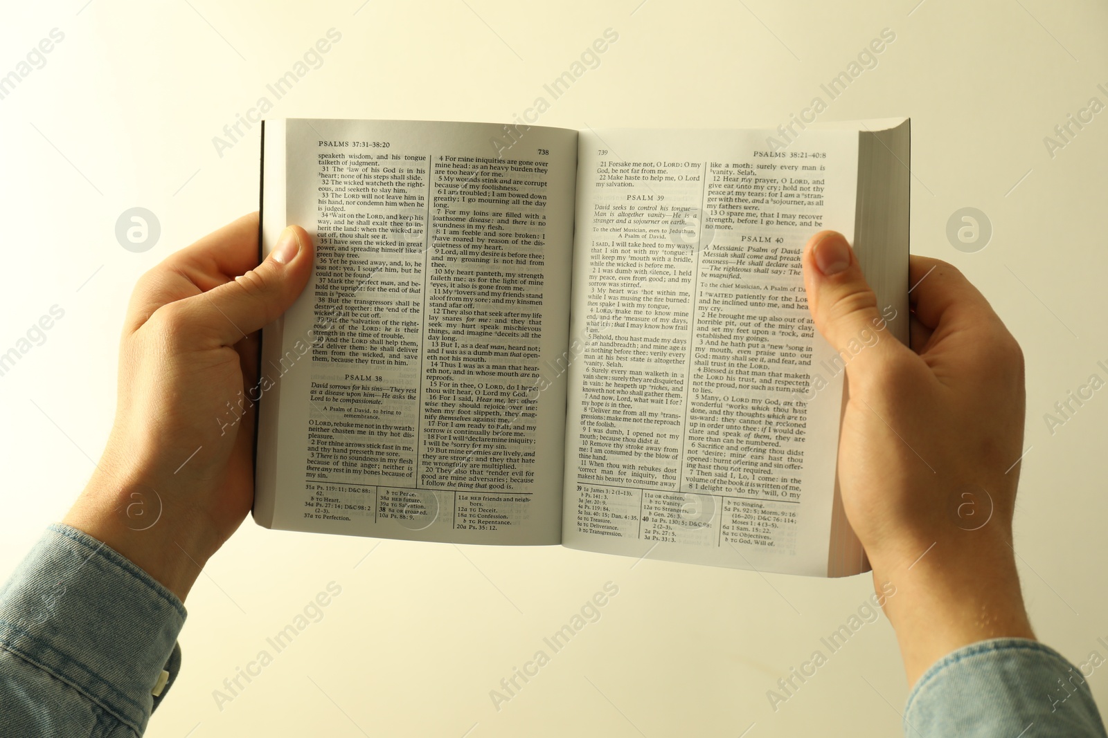 Photo of Man reading Holy Bible in English language on light background, closeup