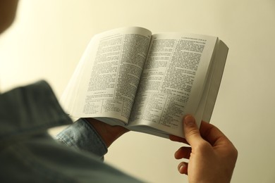 Photo of Man reading Holy Bible in English language on light background, closeup