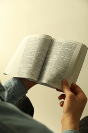 Photo of Man reading Holy Bible in English language on light background, closeup