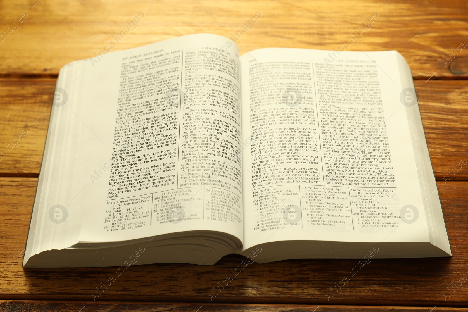 Photo of Open Holy Bible in English language on wooden table, closeup