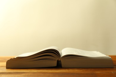 Photo of Open Holy Bible in English language on wooden table, closeup