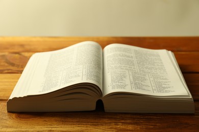 Photo of Open Holy Bible in English language on wooden table, closeup