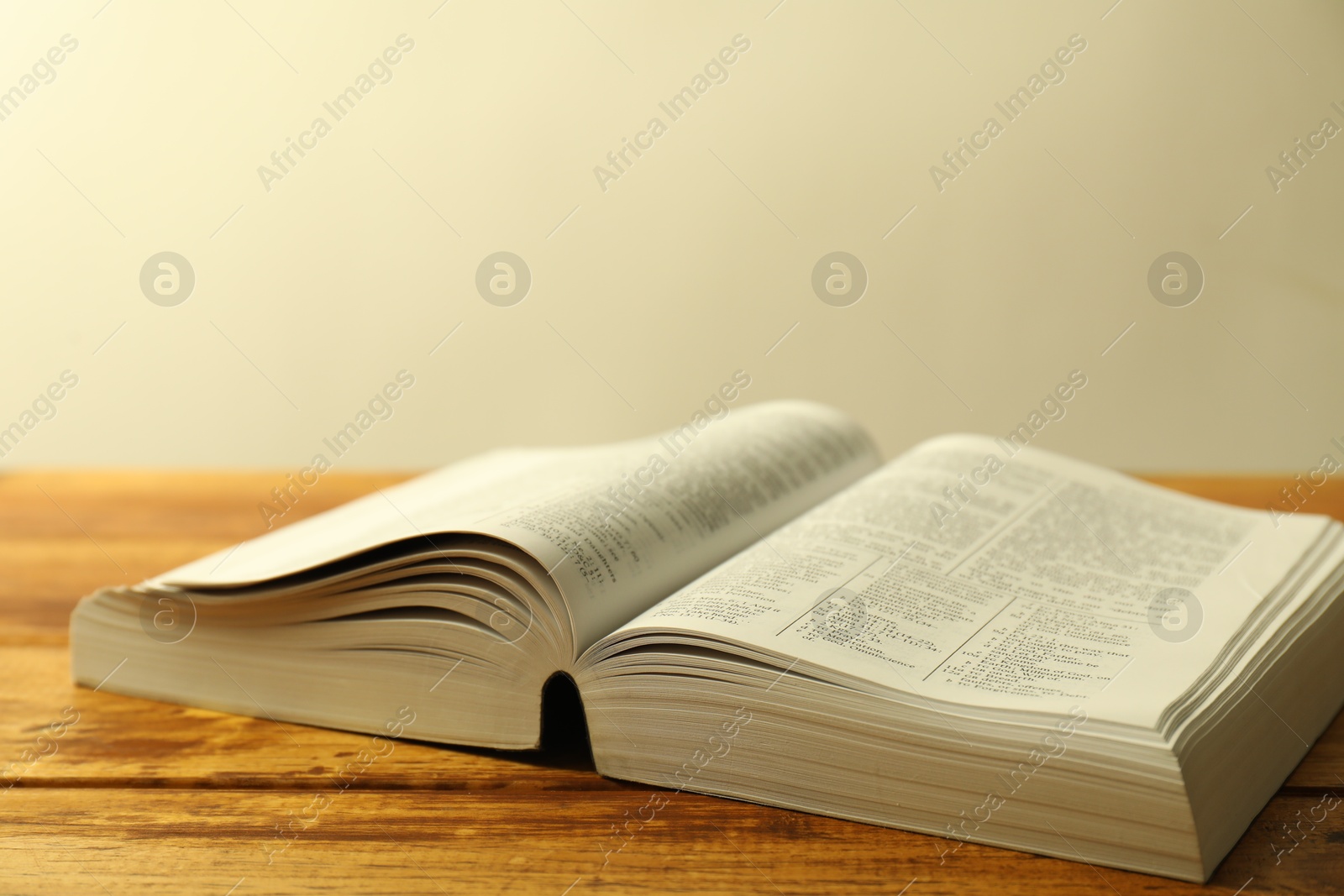 Photo of Open Holy Bible in English language on wooden table, closeup