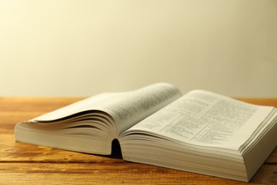 Photo of Open Holy Bible in English language on wooden table, closeup