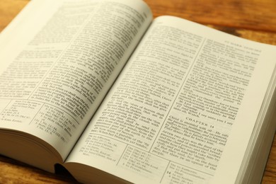 Photo of Open Holy Bible in English language on table, closeup