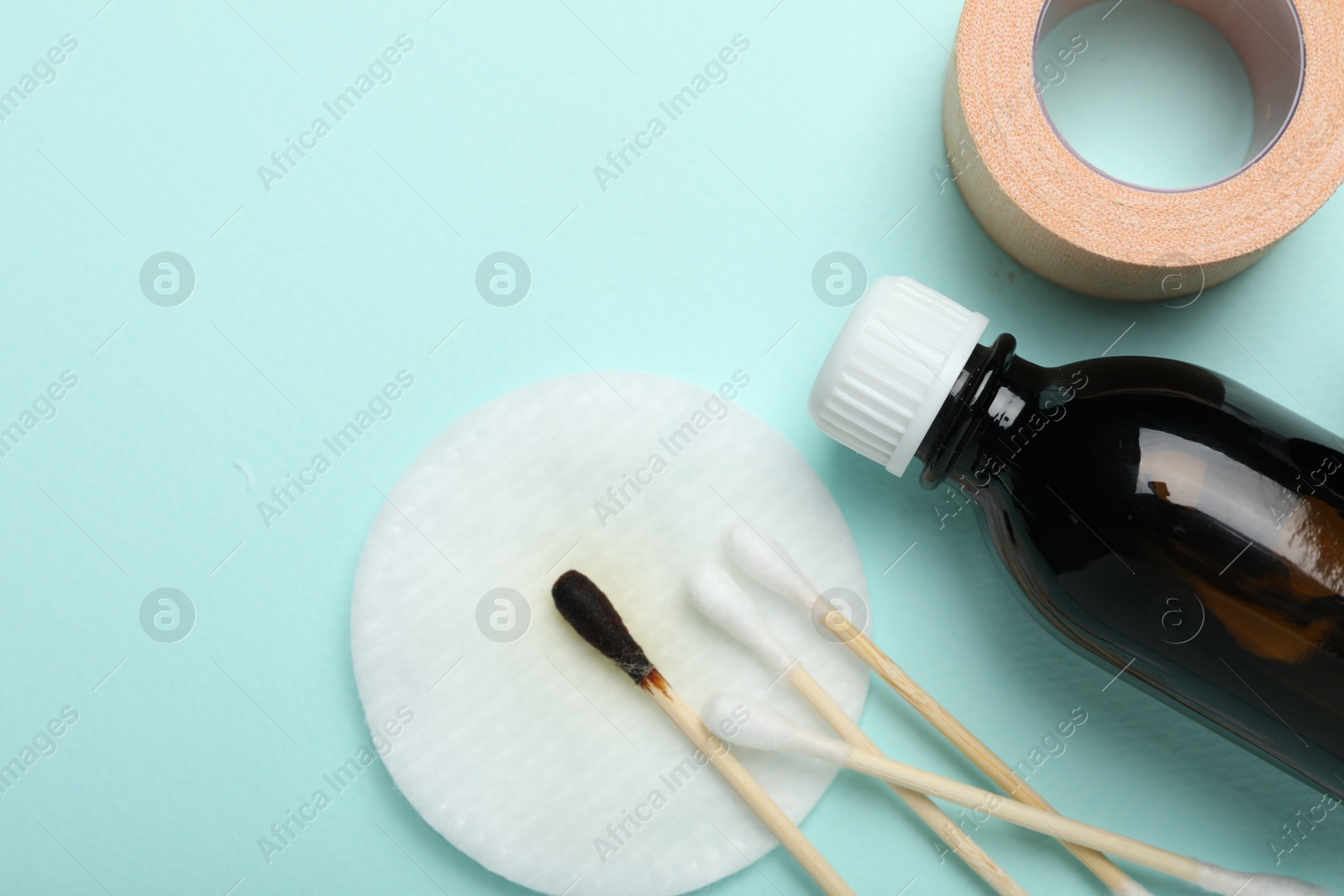 Photo of Topical iodine and other first aid kit components on light blue background, flat lay. Space for text