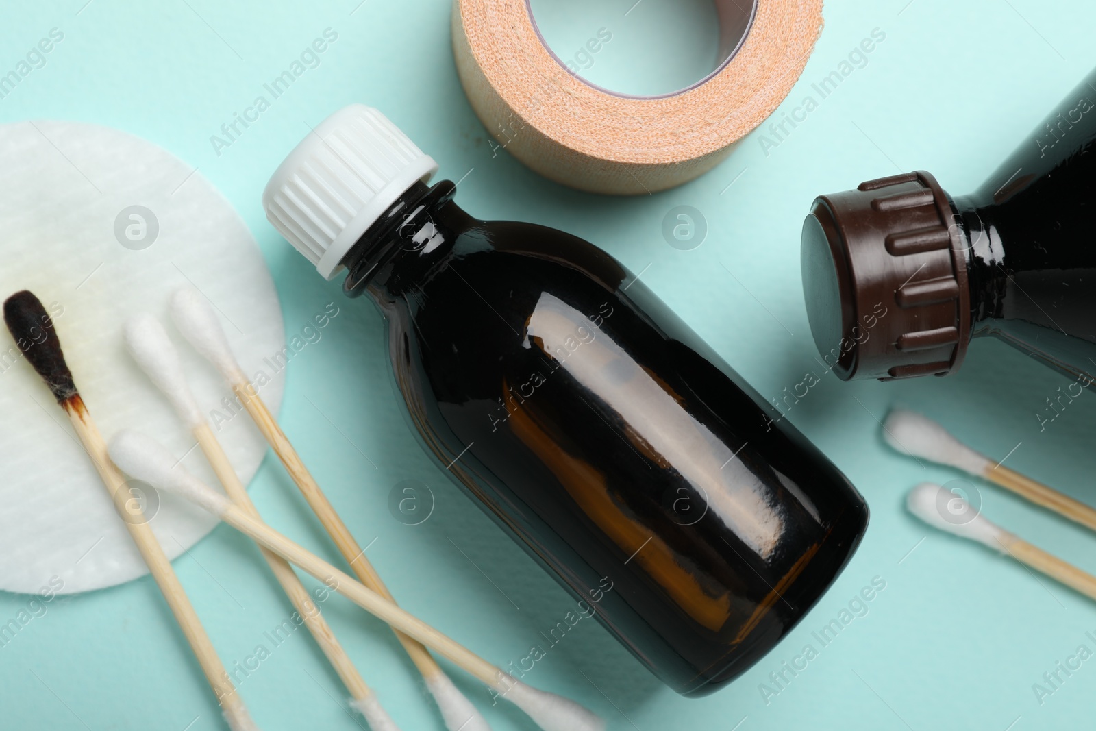 Photo of Topical iodine and other first aid kit components on light blue background, flat lay