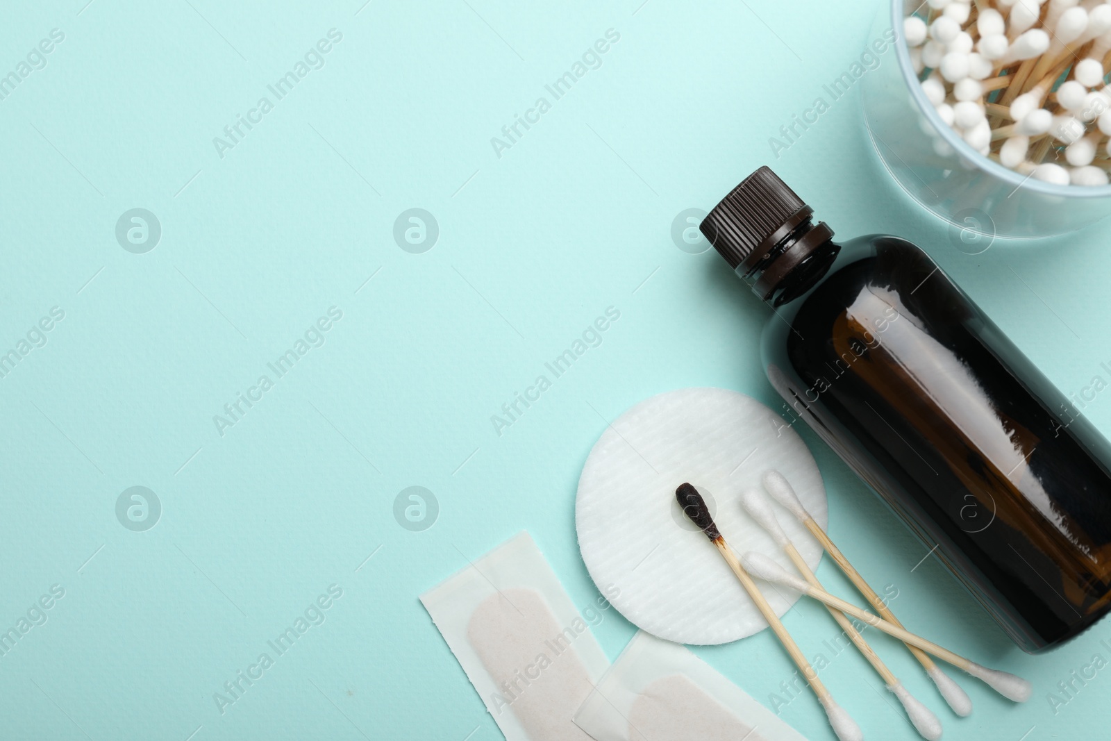 Photo of Topical iodine and other first aid kit components on light blue background, flat lay. Space for text