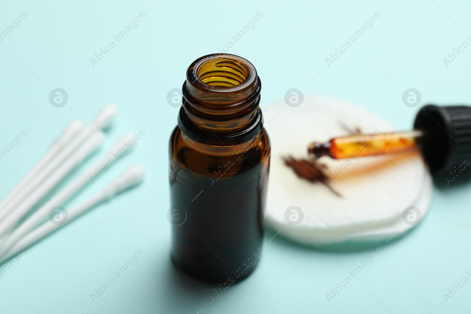 Photo of Bottle of topical iodine, cotton pads and swabs on light blue background, selective focus