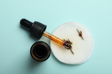 Photo of Bottle of topical iodine with dropper and cotton pad on light blue background, top view