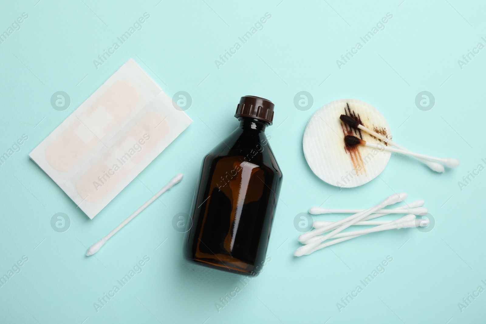 Photo of Topical iodine and other first aid kit components on light blue background, flat lay