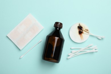 Photo of Topical iodine and other first aid kit components on light blue background, flat lay