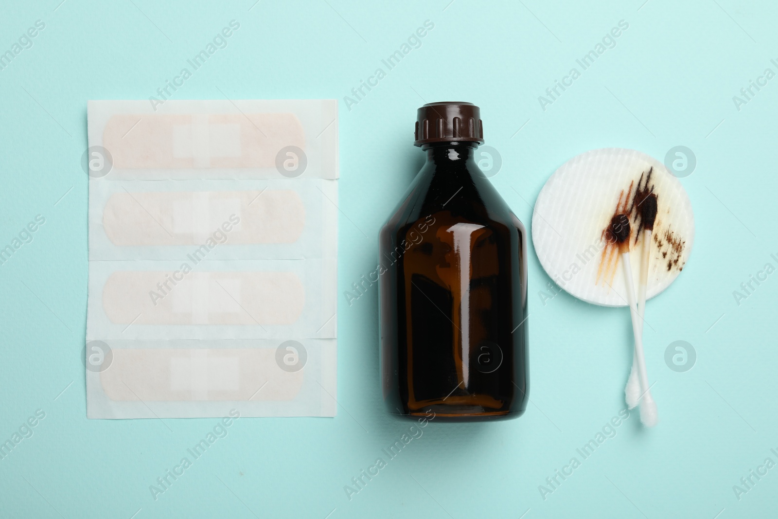 Photo of Topical iodine and other first aid kit components on light blue background, flat lay