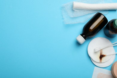 Photo of Topical iodine and other first aid kit components on light blue background, flat lay. Space for text