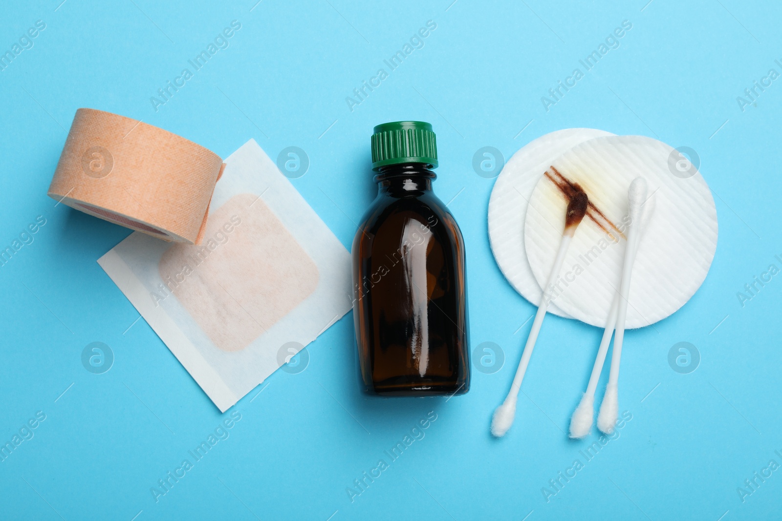 Photo of Topical iodine and other first aid kit components on light blue background, flat lay