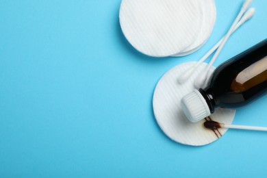 Photo of Topical iodine, cotton pads and swabs on light blue background, flat lay