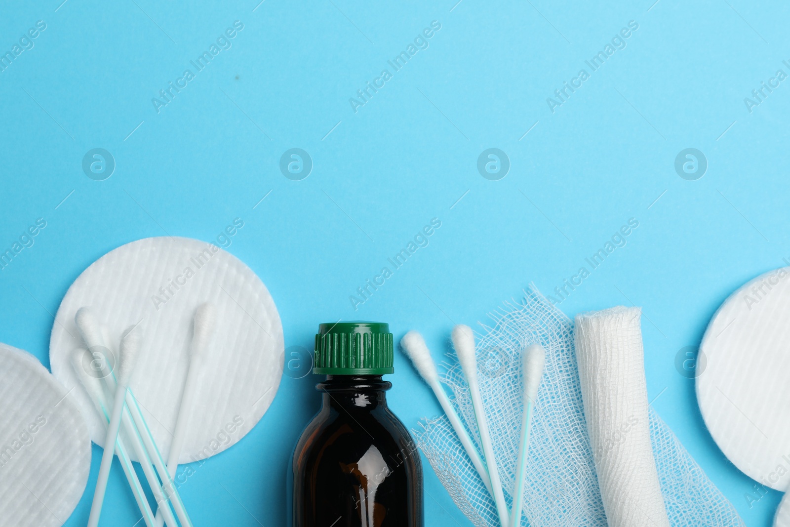 Photo of Topical iodine, bandage, cotton pads and swabs on light blue background, flat lay