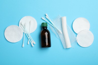 Photo of Topical iodine, bandage, cotton pads and swabs on light blue background, flat lay