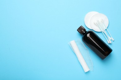 Photo of Topical iodine, bandage, cotton pads and swabs on light blue background, flat lay