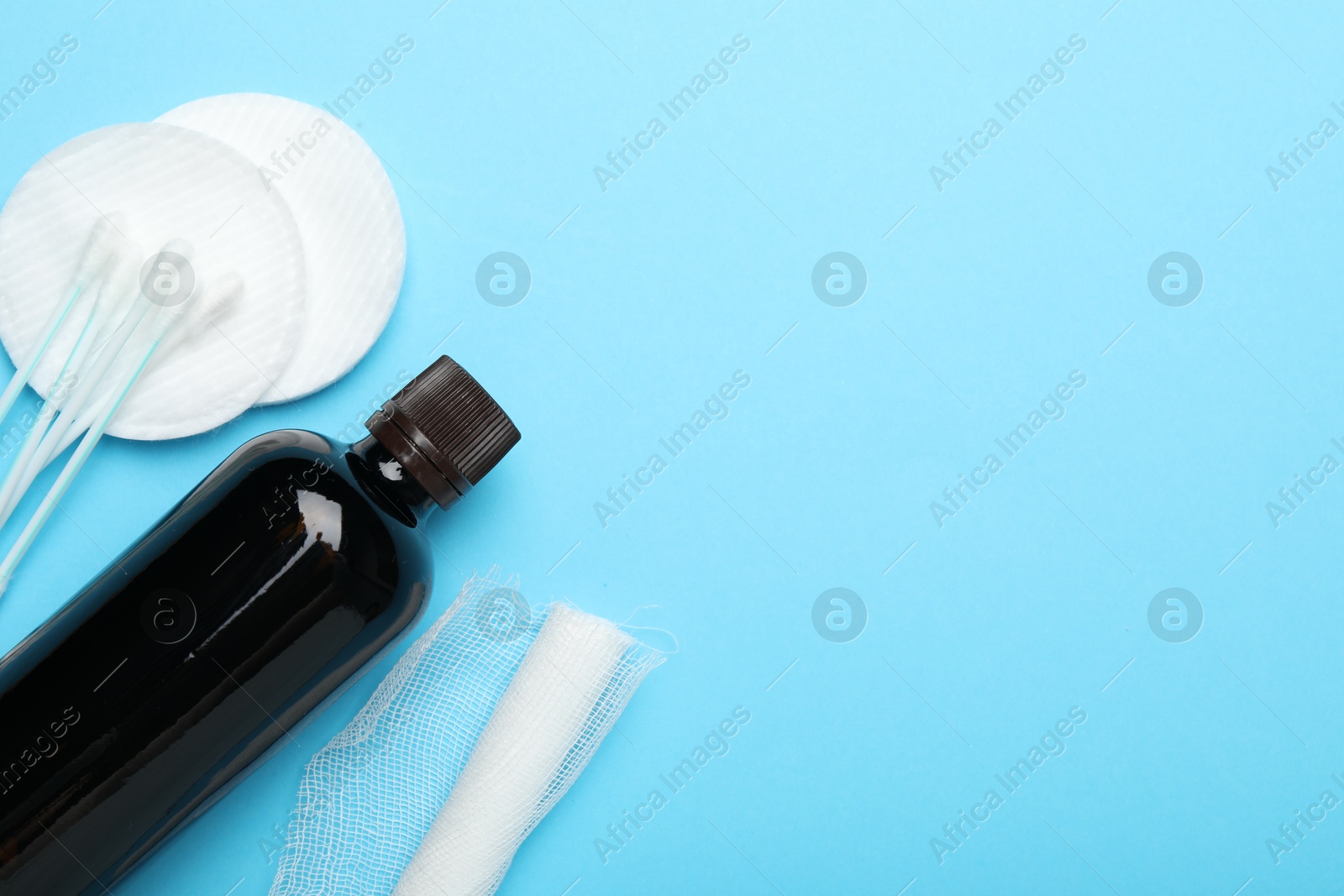 Photo of Topical iodine, bandage, cotton pads and swabs on light blue background, flat lay