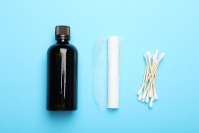 Photo of Topical iodine, bandage and cotton swabs on light blue background, flat lay