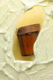 Photo of Cosmetic jar and sample of body scrub on yellow background, top view