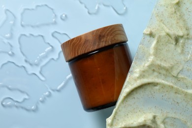 Photo of Cosmetic jar and sample of body scrub on light background, top view