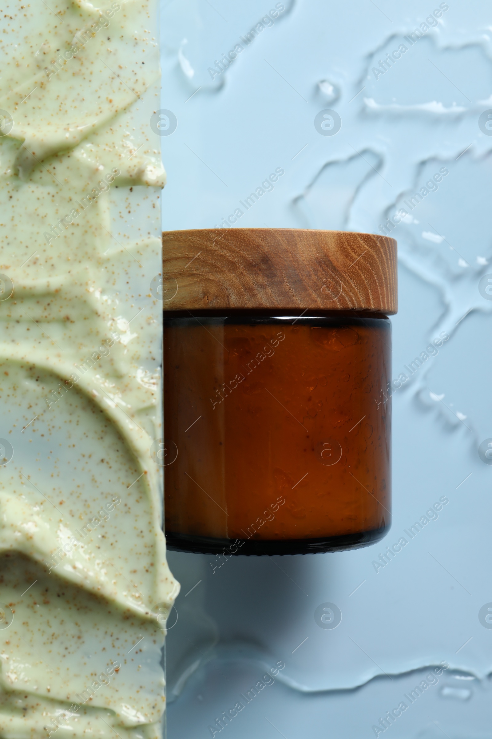 Photo of Cosmetic jar and sample of body scrub on light background, top view