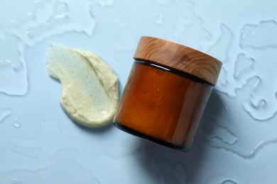 Photo of Cosmetic jar and sample of body scrub on light background, top view