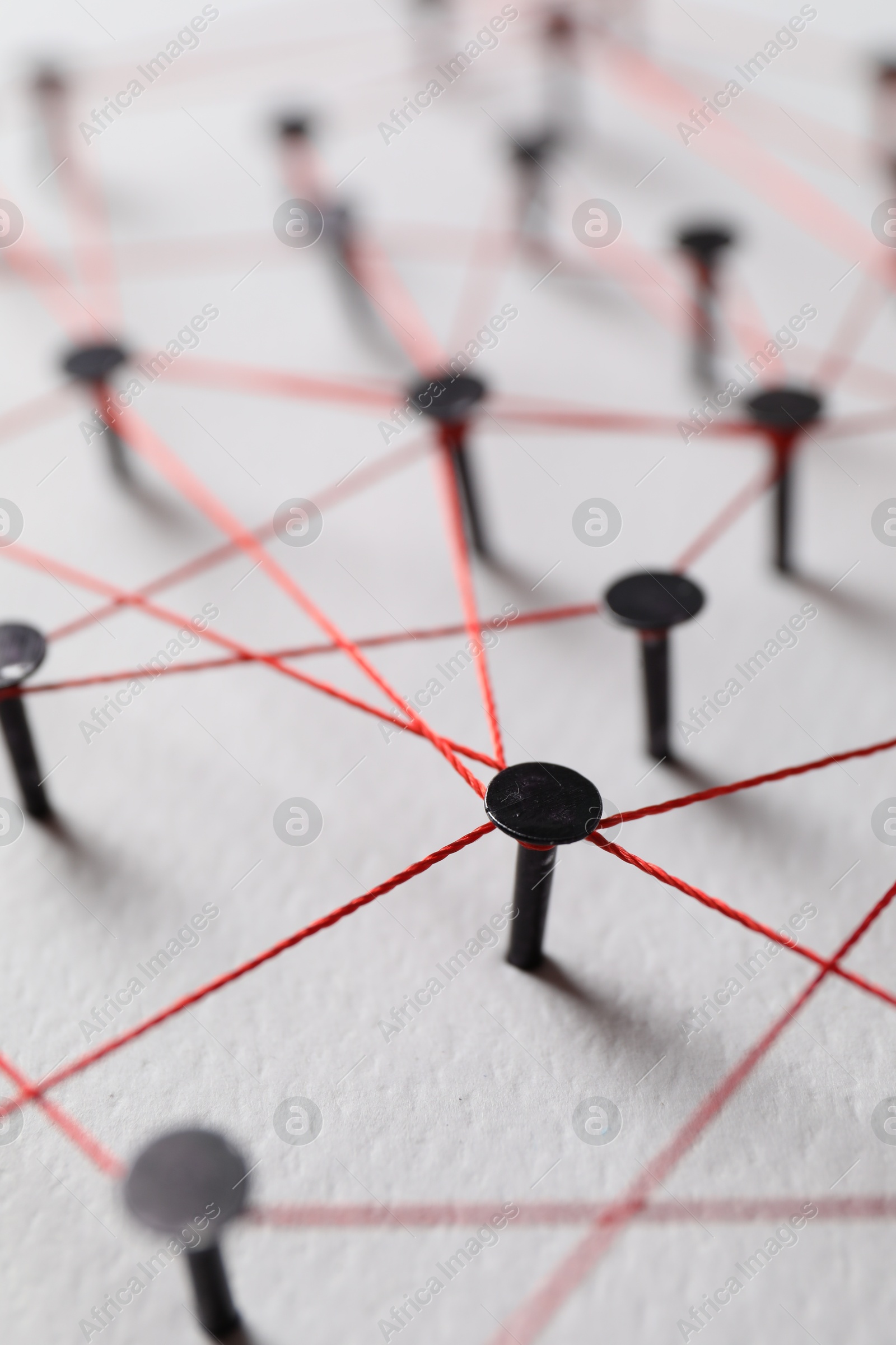 Photo of Network connection. Nails linked together by thread on white table, closeup