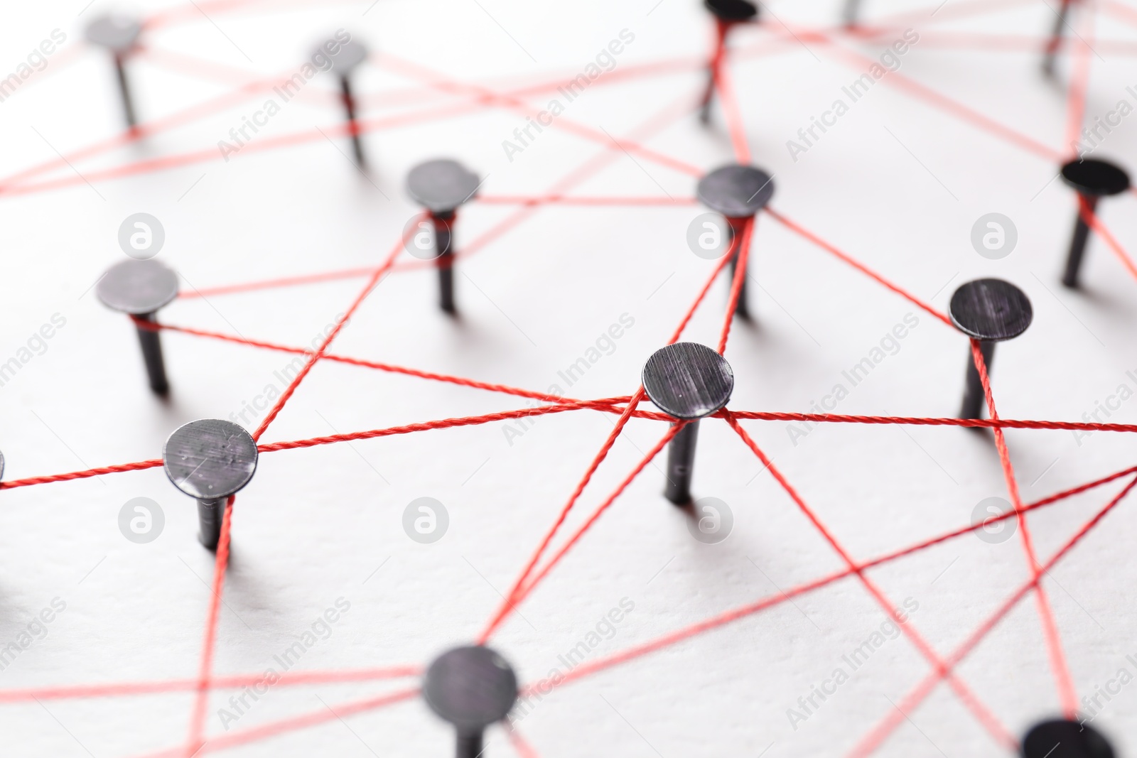 Photo of Network connection. Nails linked together by thread on white table, closeup