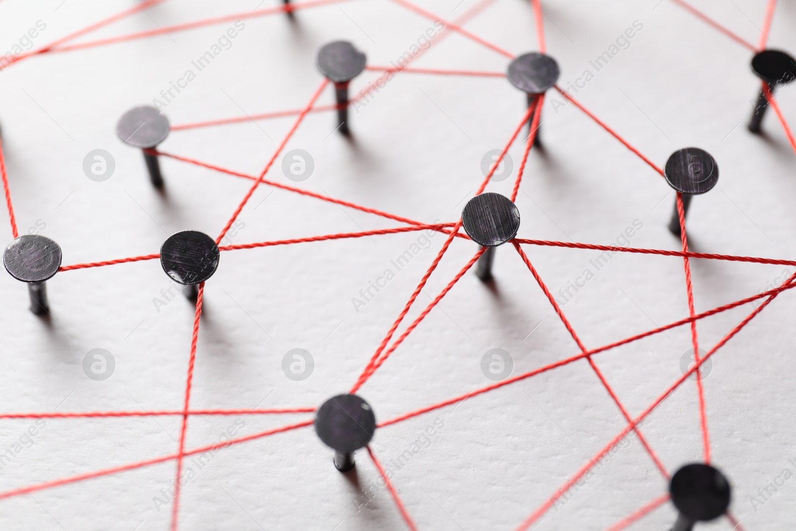 Photo of Network connection. Nails linked together by thread on white table, closeup