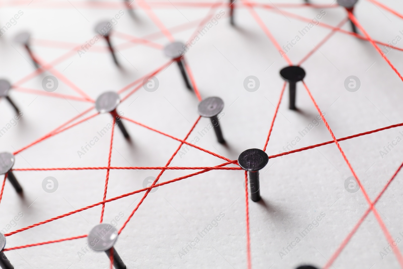 Photo of Network connection. Nails linked together by thread on white table, closeup