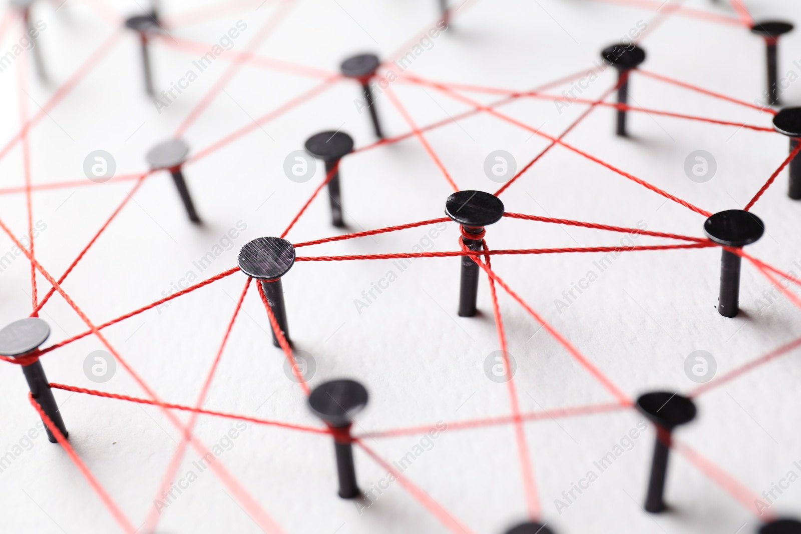 Photo of Network connection. Nails linked together by thread on white table, closeup