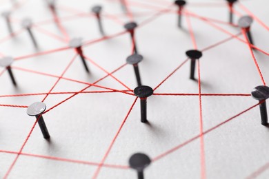 Photo of Network connection. Nails linked together by thread on white table, closeup