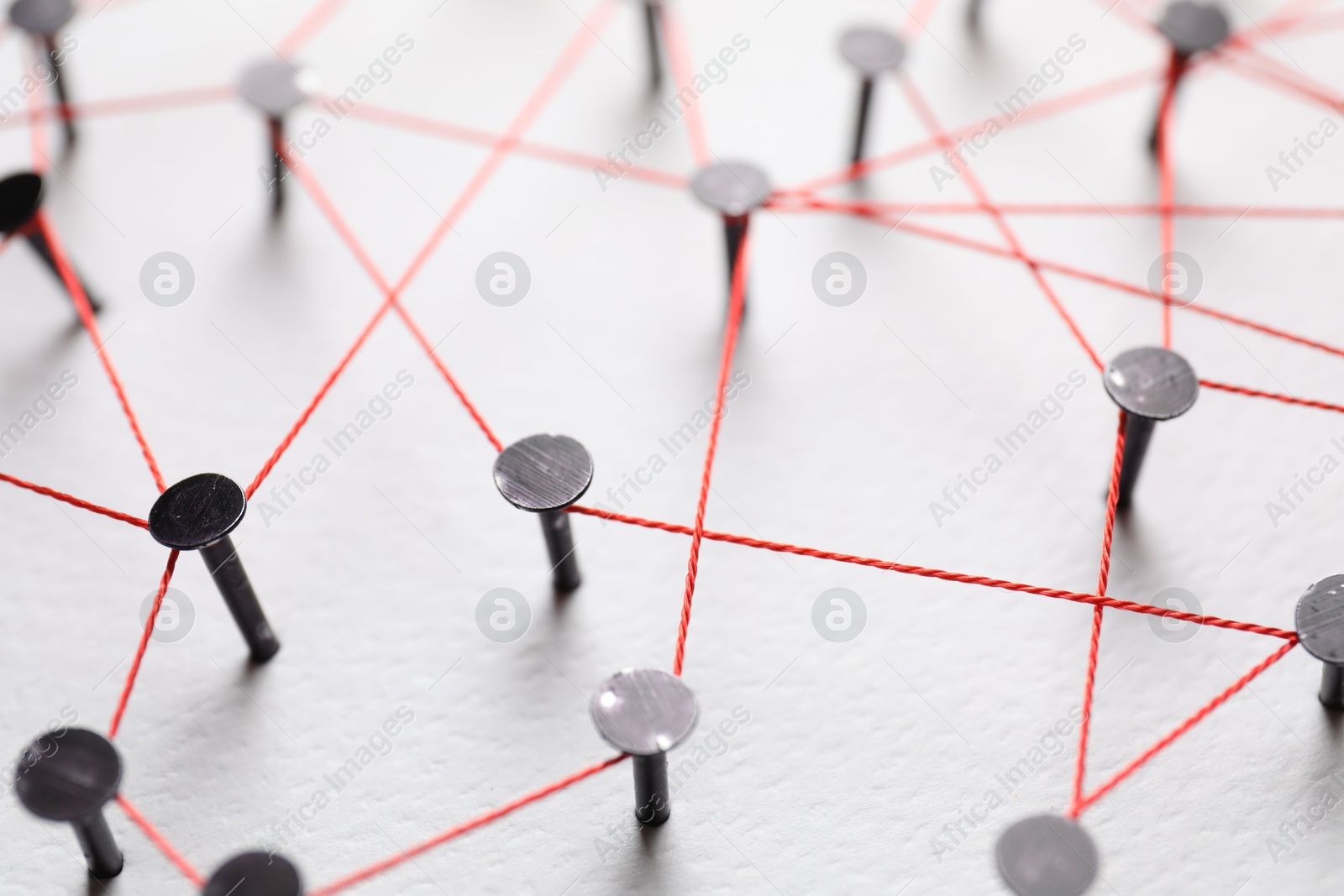 Photo of Network connection. Nails linked together by thread on white table, closeup