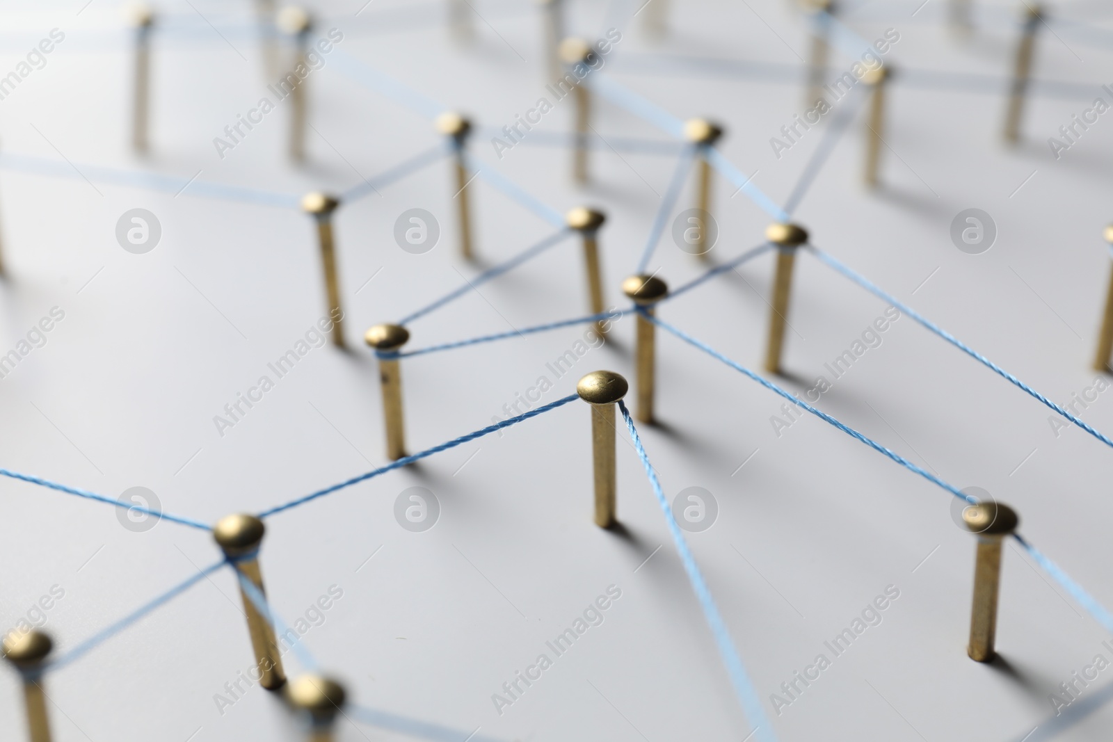 Photo of Network connection. Nails linked together by thread on white table, closeup